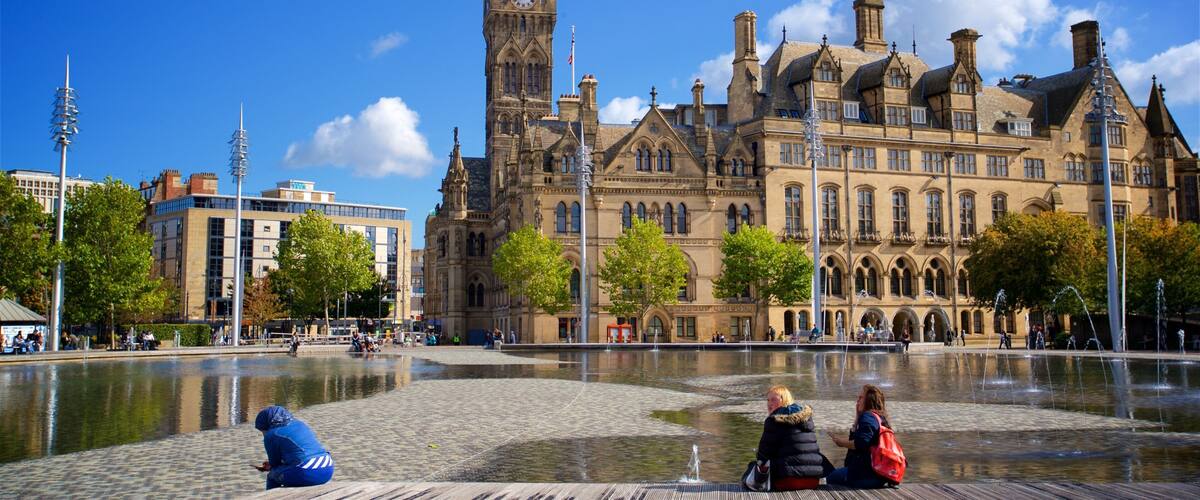 A historic building with a clock tower, a fountain, and a cobblestone plaza.