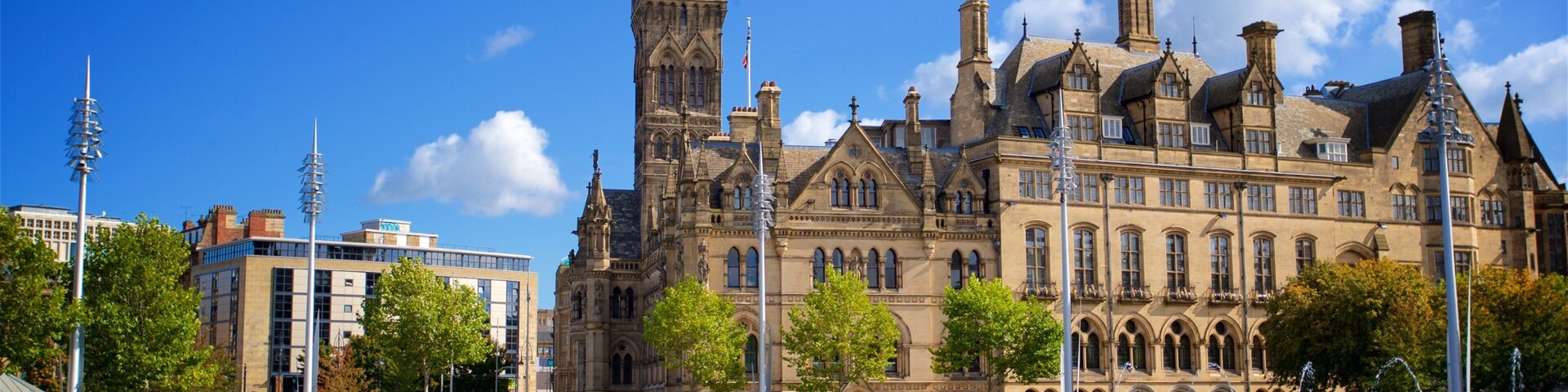 A historic building with a clock tower, a fountain, and a cobblestone plaza.