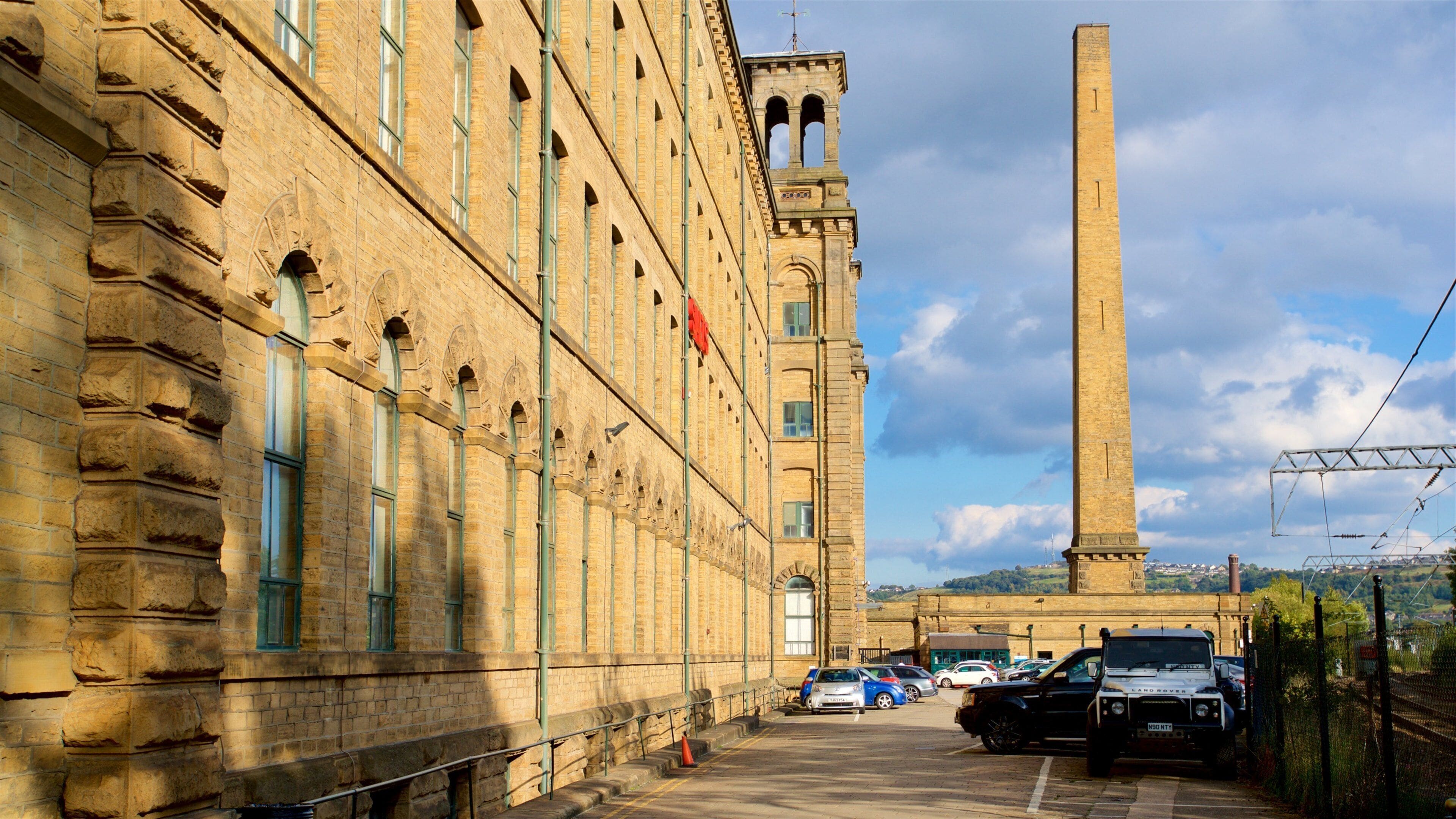 A historic building with a tall tower and a parking lot with cars.
