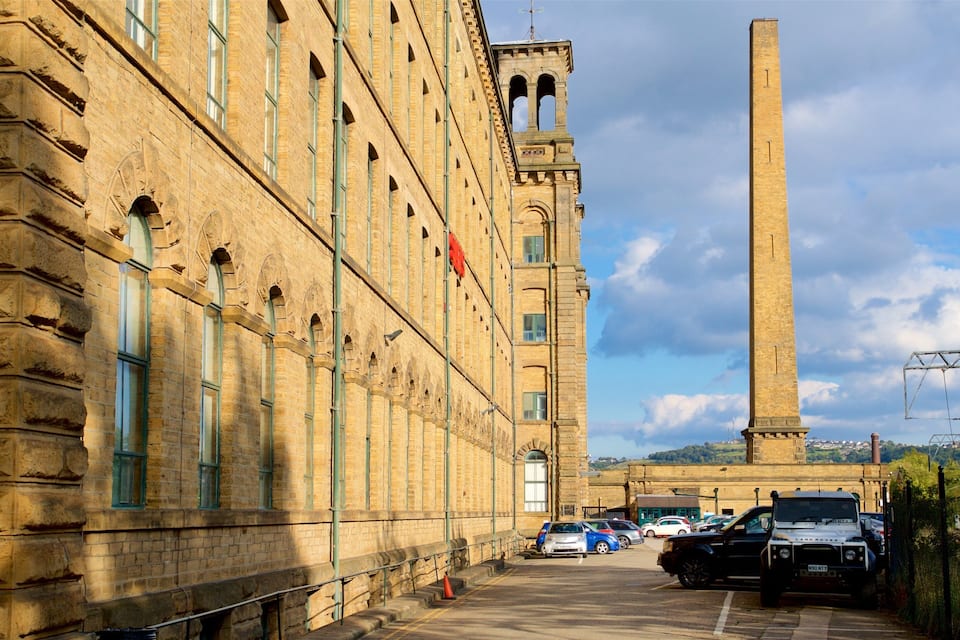 Un edifici històric amb una torre alta i un aparcament ple de cotxes.
