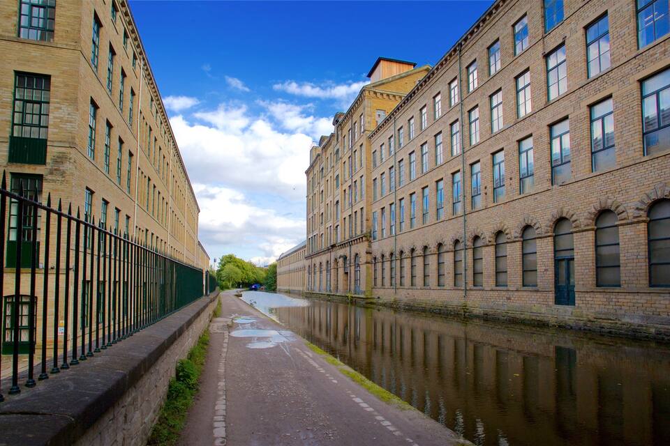 Een gracht omzoomd door historische gebouwen met bakstenen gevels en grote ramen, onder een heldere blauwe lucht.
