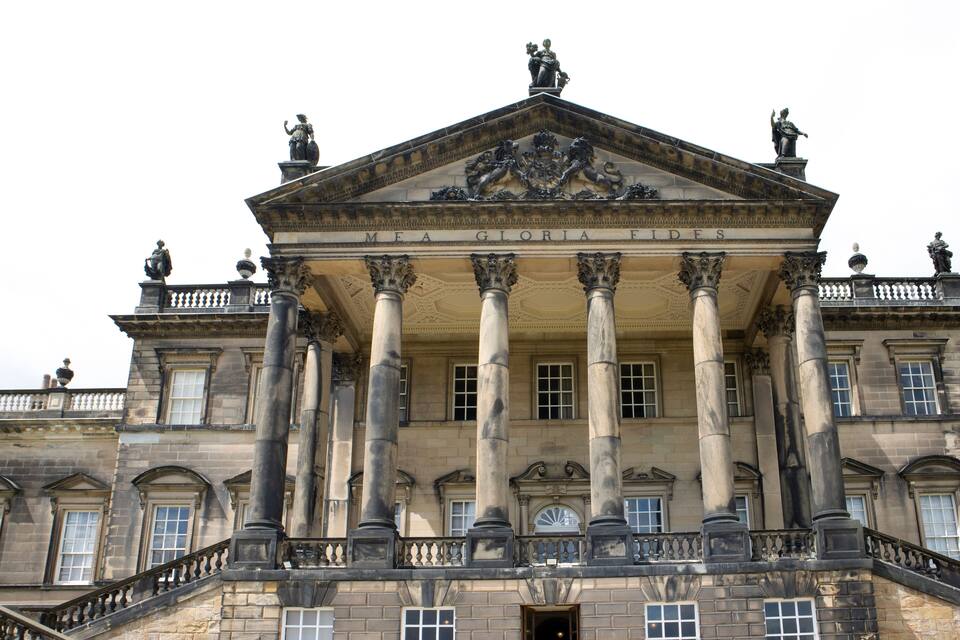 A grand building with classical architecture, featuring a prominent entrance with columns and a decorative crest above.