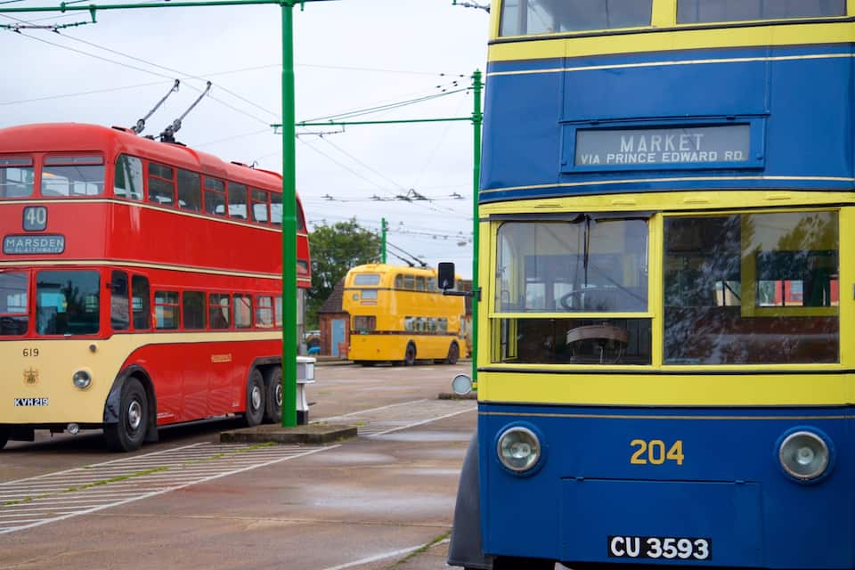 A red double-decker bus with the number 40 and a blue double-decker bus with the number 204 parked at a tram stop.