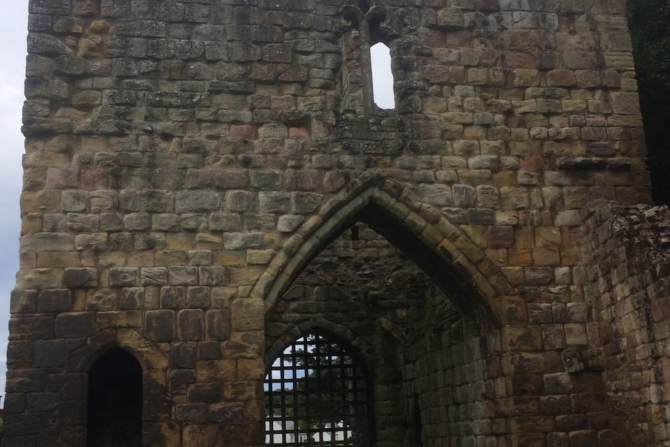 Ruínas de um castelo de pedra, com uma entrada em arco e uma pequena janela acima.