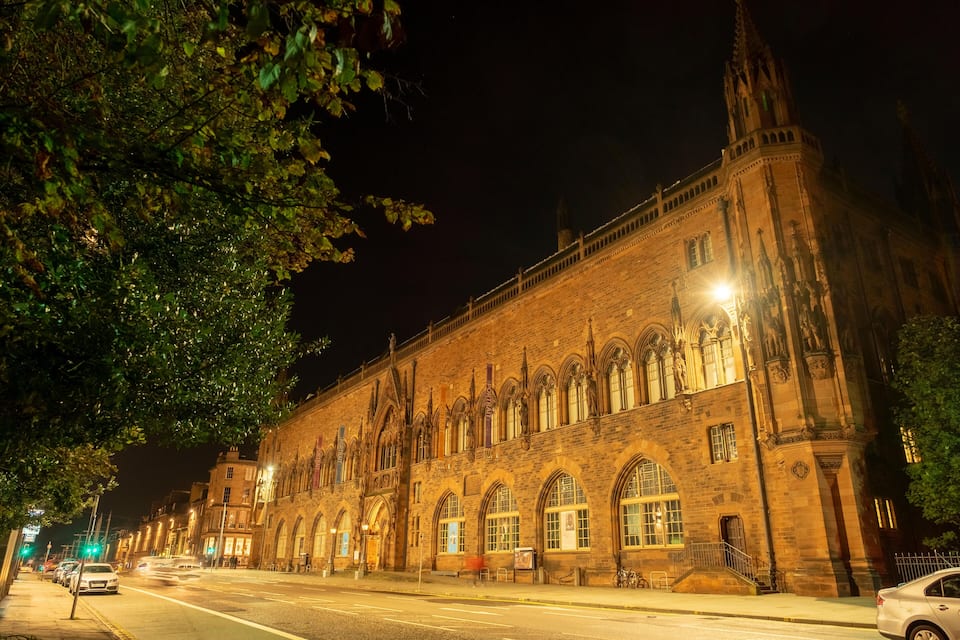 Un edificio histórico con ventanas de arco y arquitectura gótica, visto de noche.