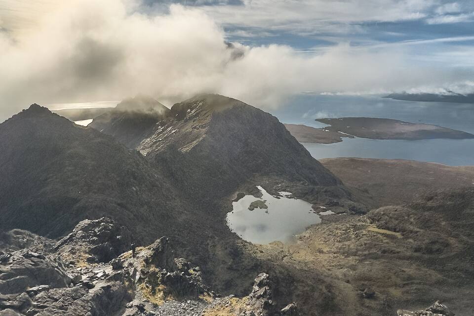 A mountainous landscape with a lake and a sunlit sky.