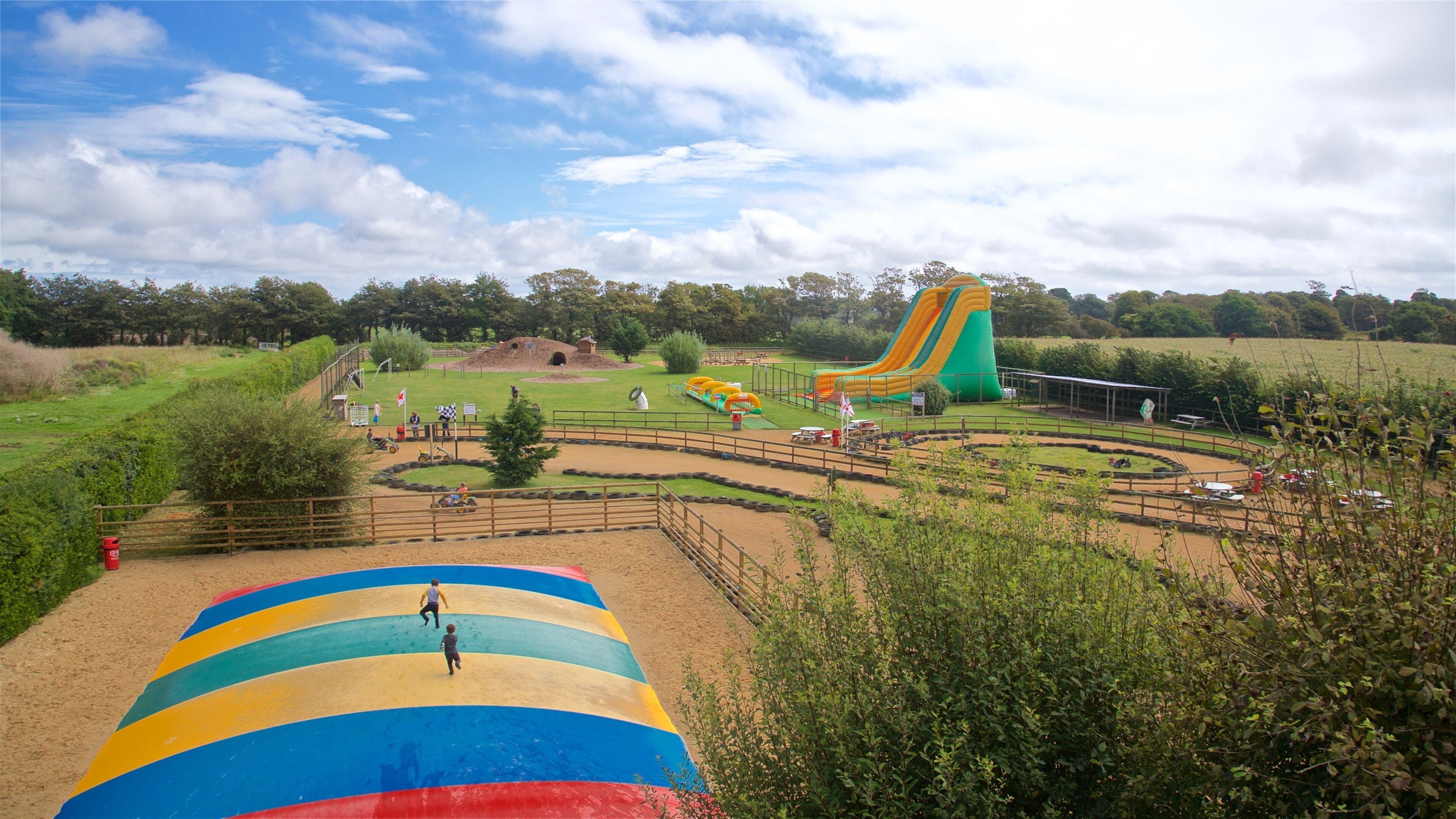 A colorful playground with a large slide, a sandy area, and a fenced enclosure.