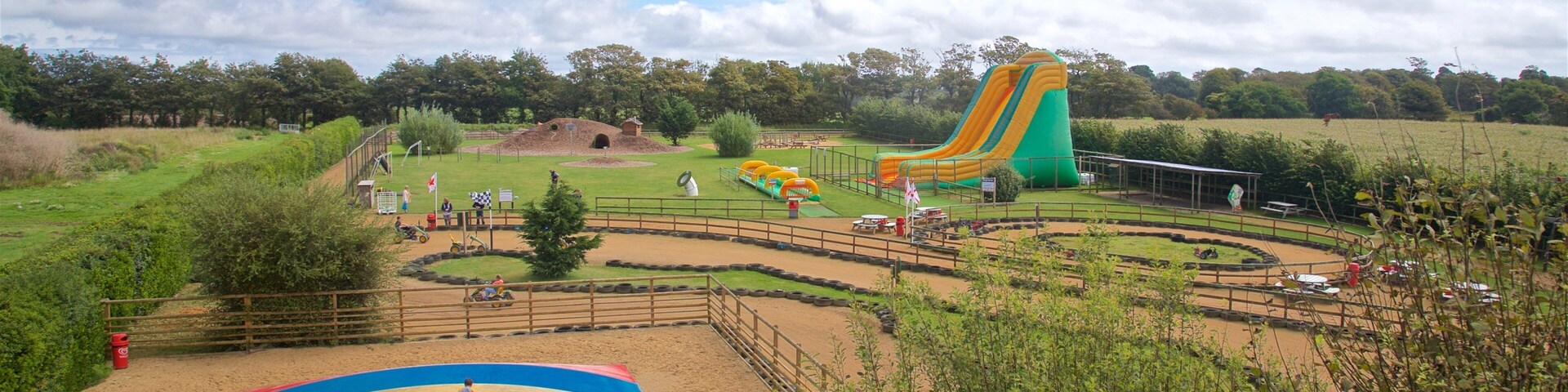 Un parque infantil colorido con un tobogán grande, una zona de arena y un cerramiento.
