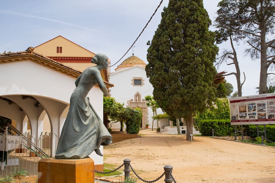 A statue of a woman in a dress, a church with a dome, and a signboard.