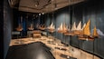 A museum exhibit with several wooden sailing ships on display.