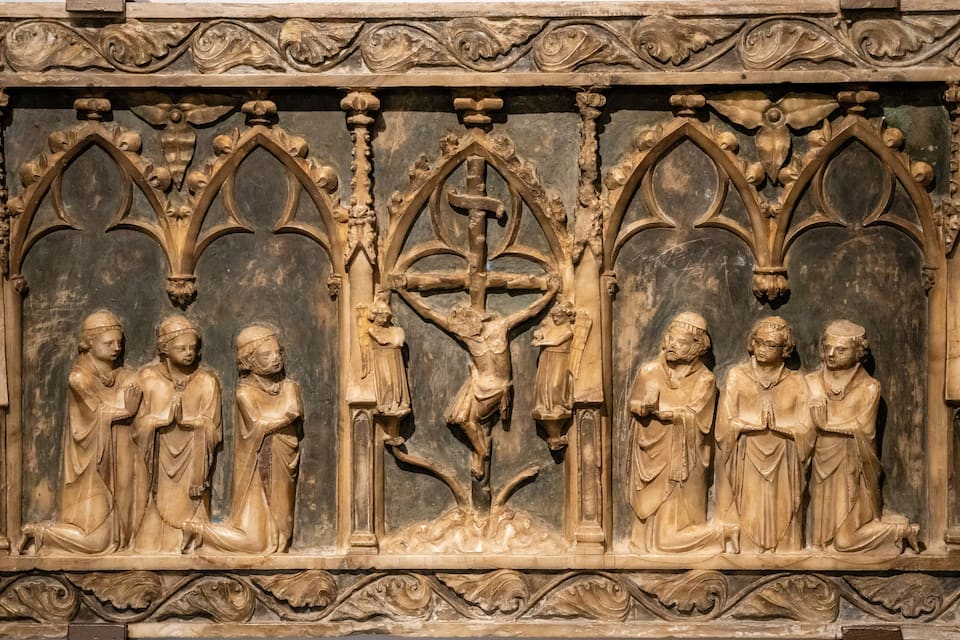 A detailed stone carving of a crucifixion scene with figures kneeling and praying.