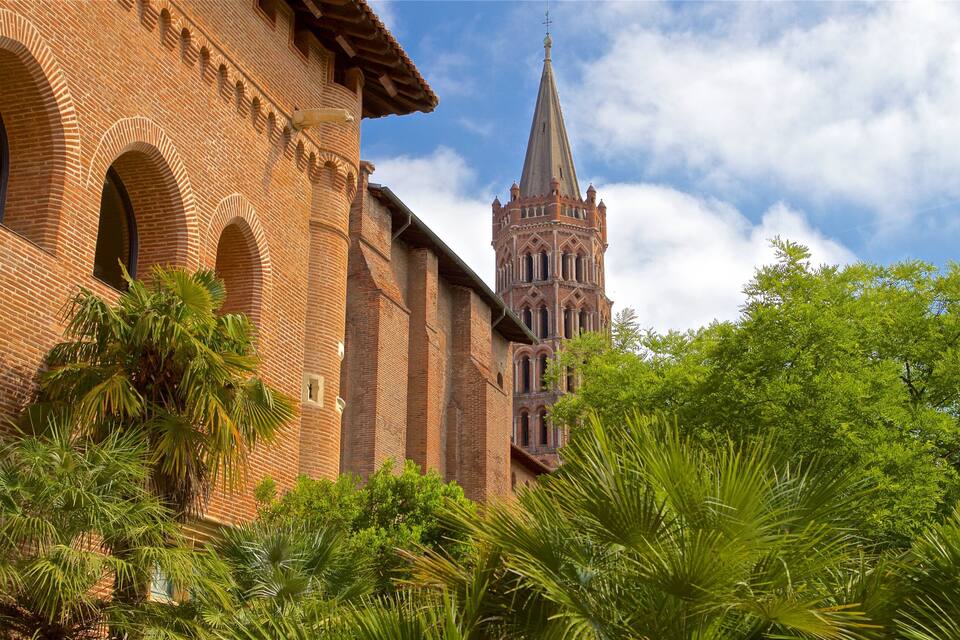 A brick building with arched windows and a tower with a pointed spire.