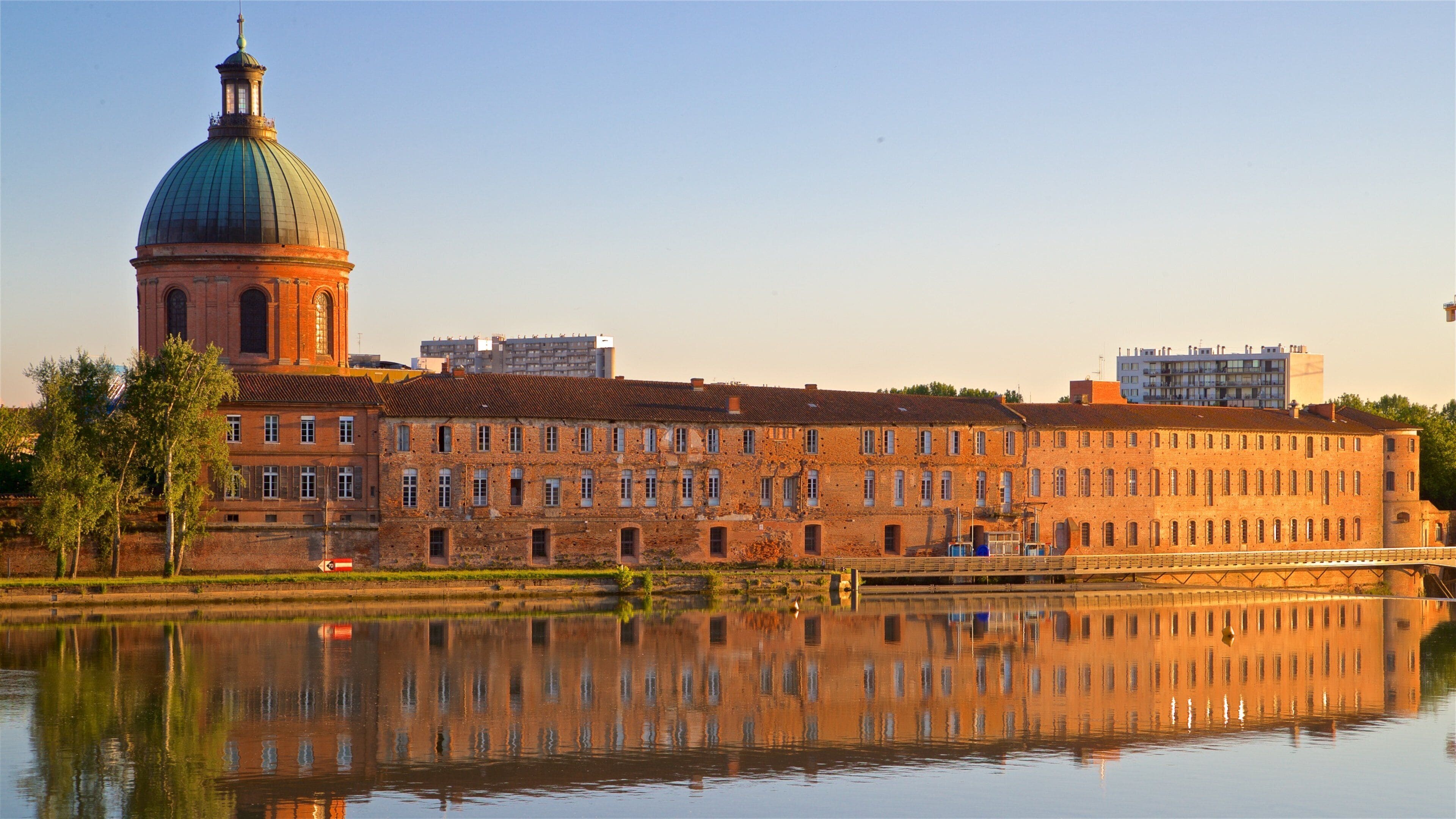 A historic building with a dome and a river in the foreground.