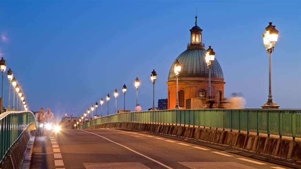 A bridge with street lamps and a large dome structure in the background.