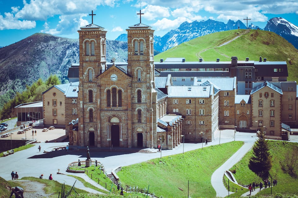 A historic church with two towers and a mountain backdrop.