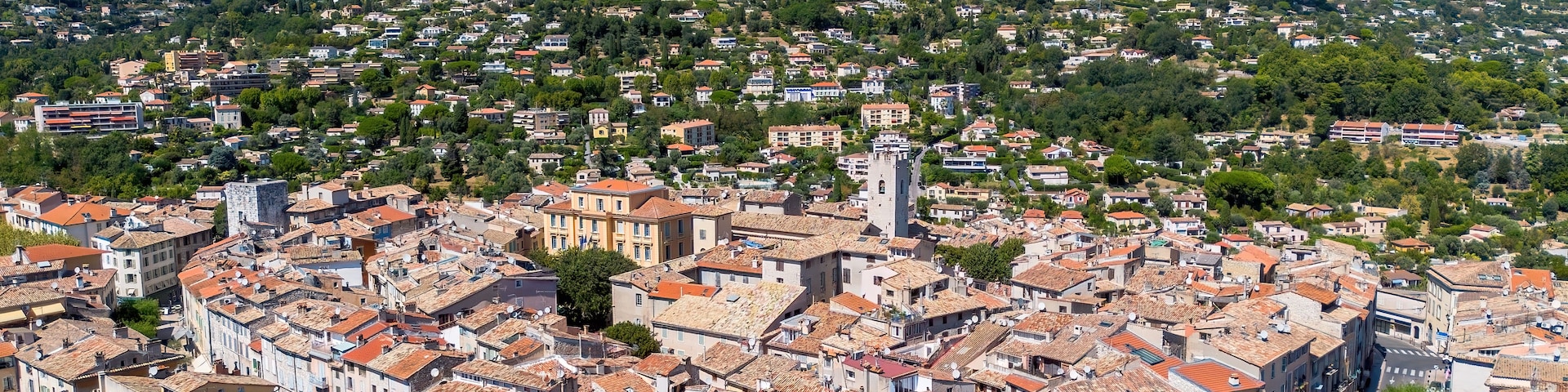 Un pueblo con edificios históricos, una imponente torre de iglesia y una montaña al fondo.