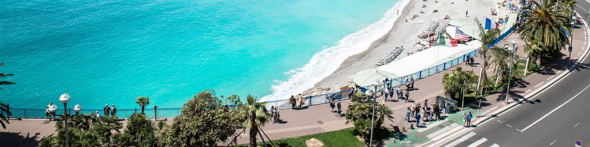 Una ciudad costera con una playa extensa, aguas turquesas cristalinas y un paseo marítimo bordeado de palmeras.