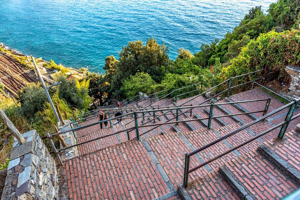 A stone staircase leading down to a coastal area with a view of the sea.