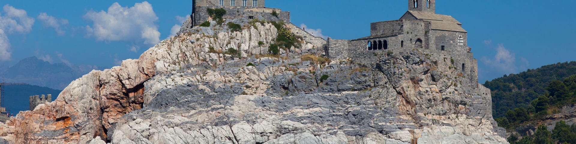 Una isla rocosa con un edificio de piedra y un campanario.