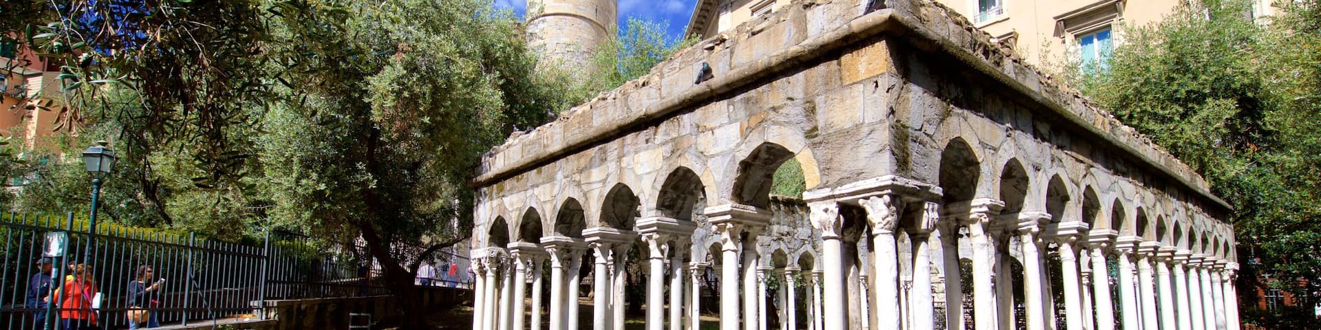 Una antigua estructura de piedra con columnas, rodeada de árboles y un sendero de piedra.