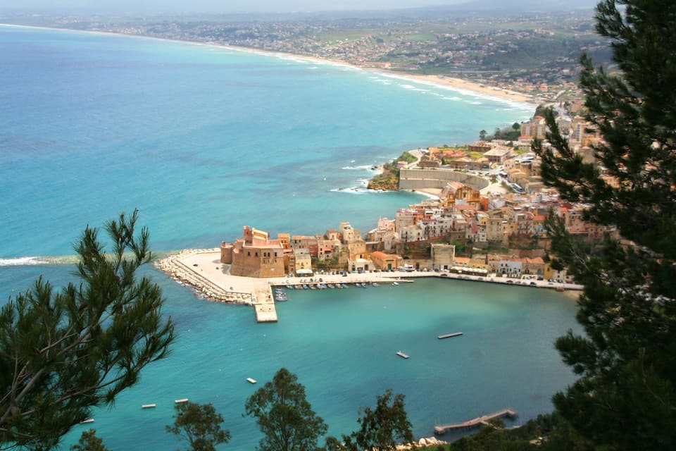 A coastal town with a historic fort, clear turquoise waters, and a beach.