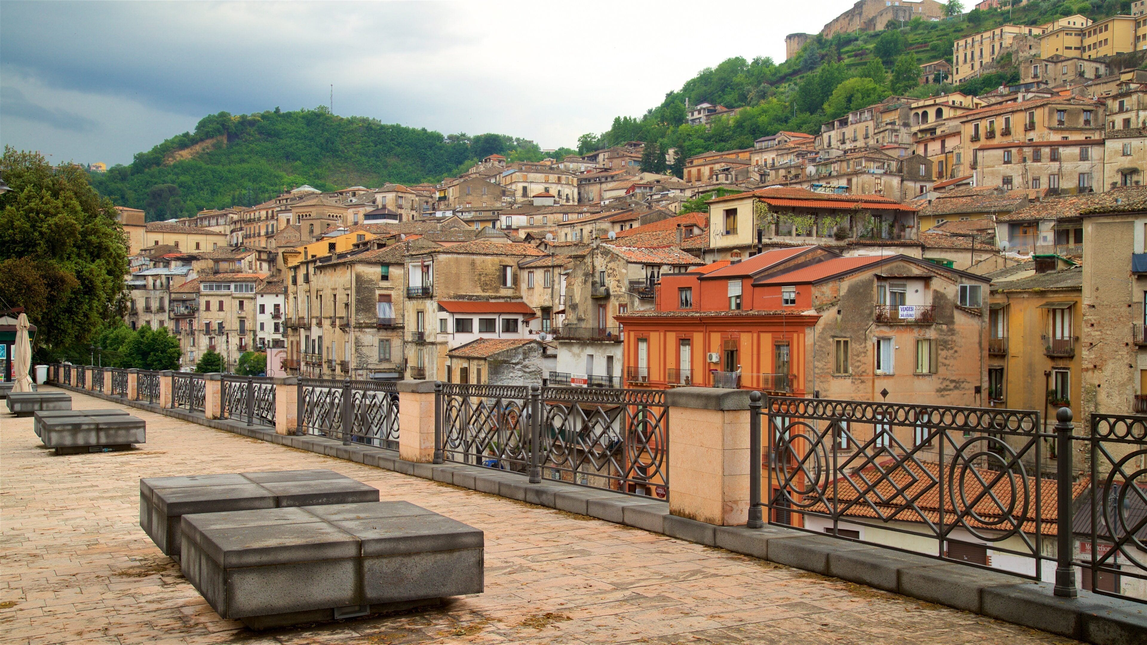 A historic town with terracotta-roofed buildings, a cobblestone street, and a hillside backdrop.