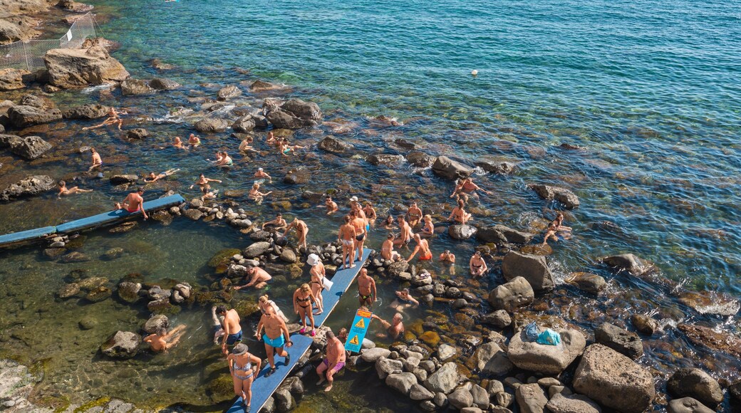 Bay of Sorgeto showing rocky coastline and general coastal views as well as a small group of people