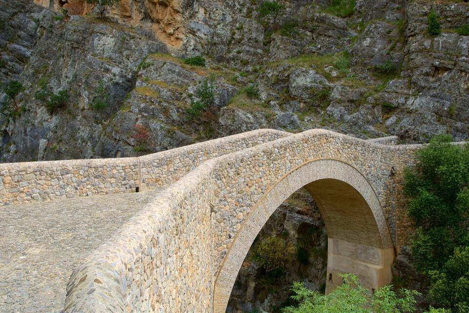 Un puente de piedra con arco sobre un desfiladero rocoso.