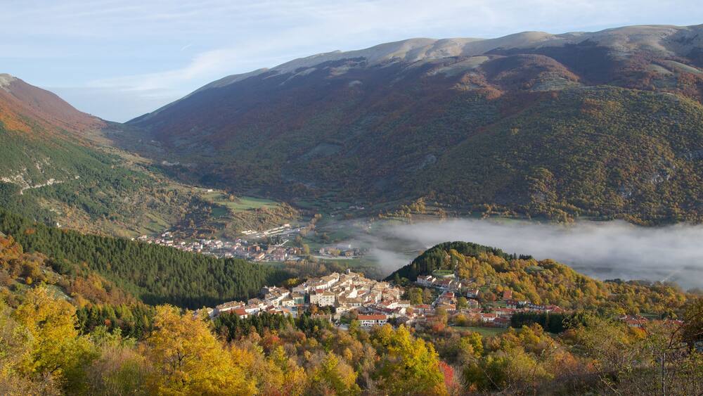 A valley with a town surrounded by mountains and autumn foliage.