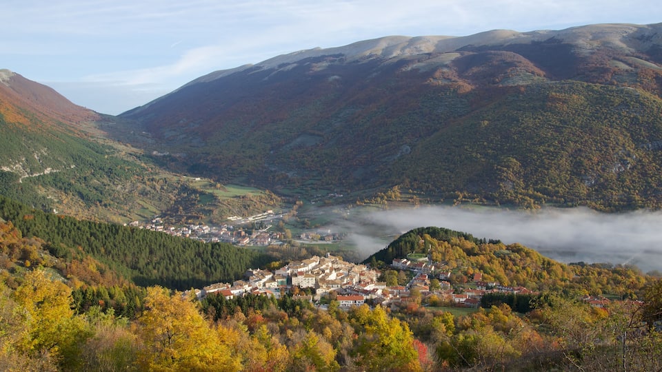 A valley with a town surrounded by mountains and autumn foliage.
