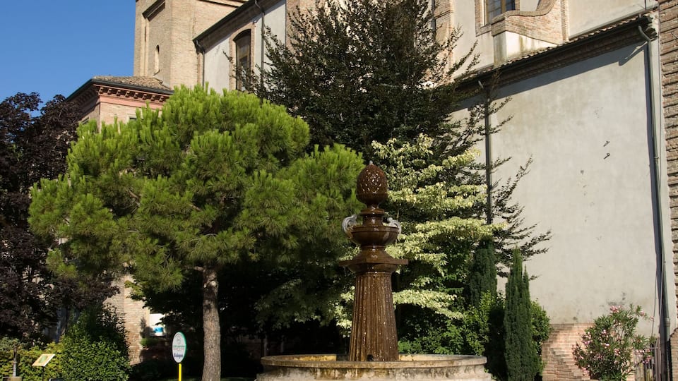 A church with a tall bell tower and a fountain in the courtyard.