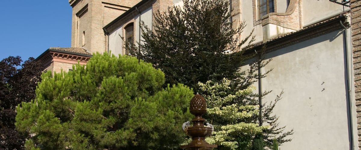 A church with a tall bell tower and a fountain in the courtyard.
