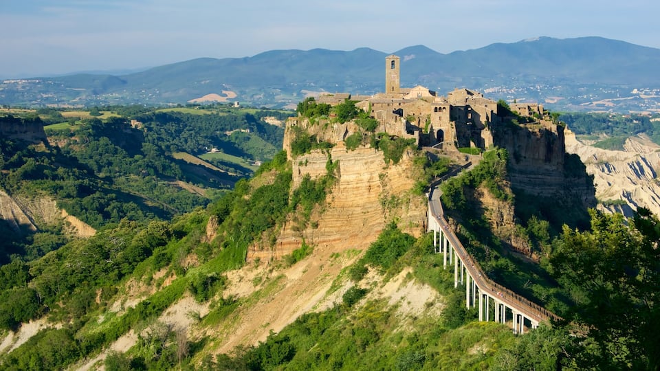 A historic castle perched atop a cliff, surrounded by lush greenery and a valley.