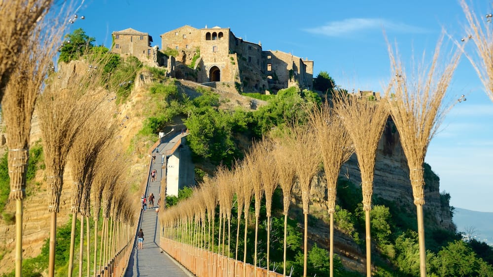 A stone castle on a hill with a pathway lined with tall, thin trees.