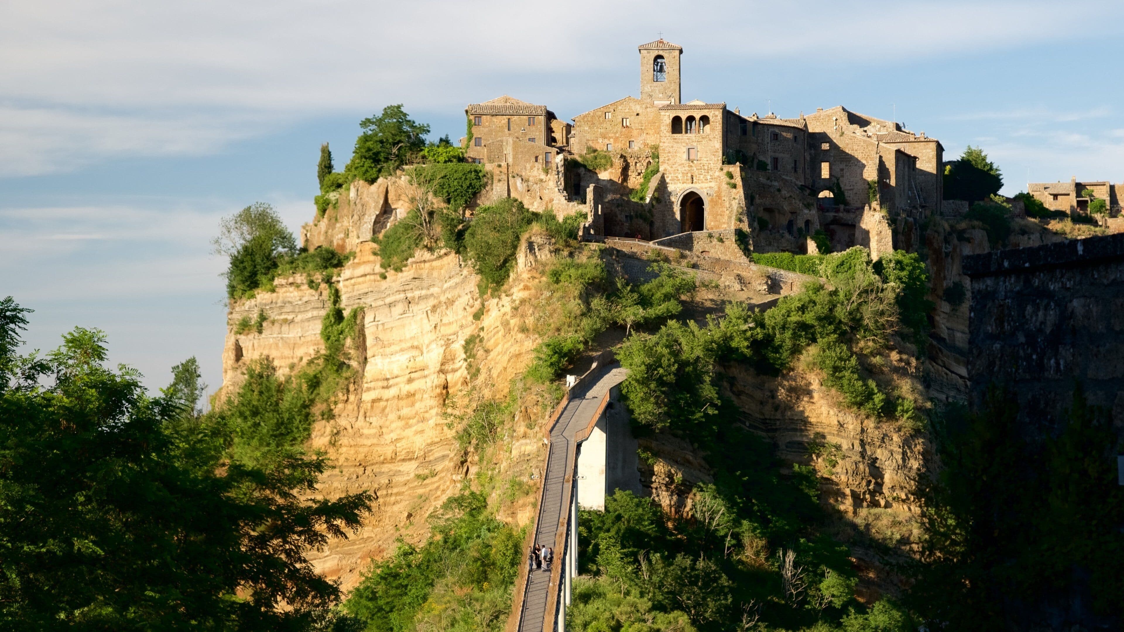 A historic stone castle atop a cliff with a narrow road leading up.