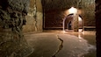 An underground stone tunnel with a single illuminated archway.