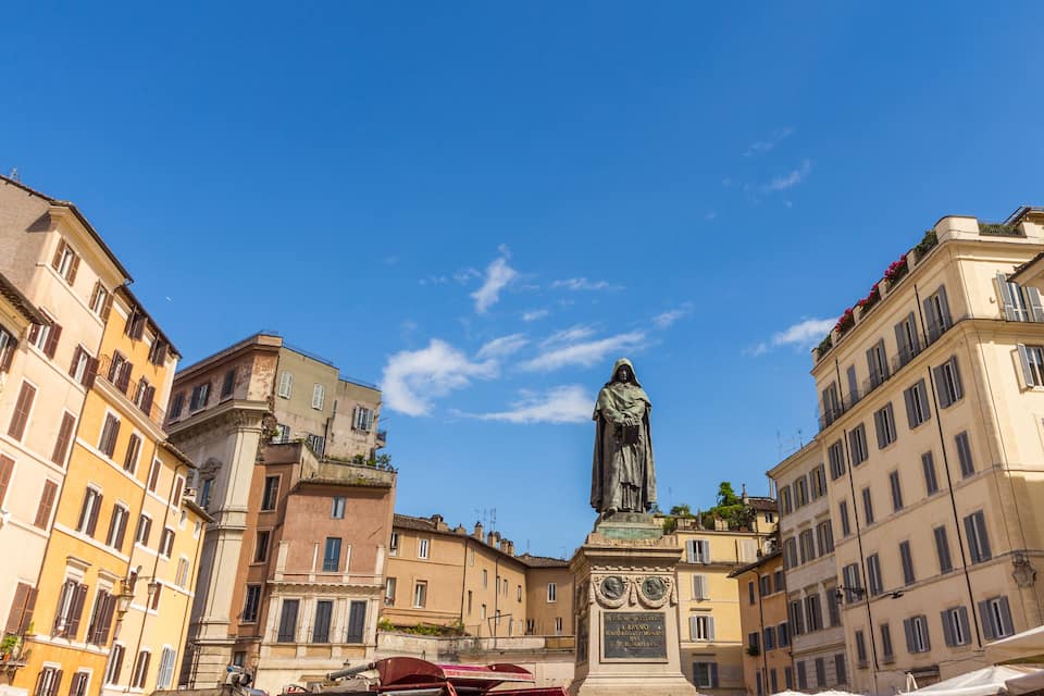 A statue in a square surrounded by historic buildings.