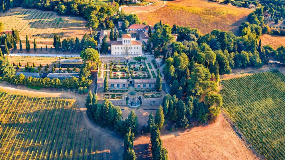 Ein Luftbild eines weitläufigen Anwesens mit ausgedehnten Weinbergen, einem formalen Garten und einem markanten Herrenhaus.