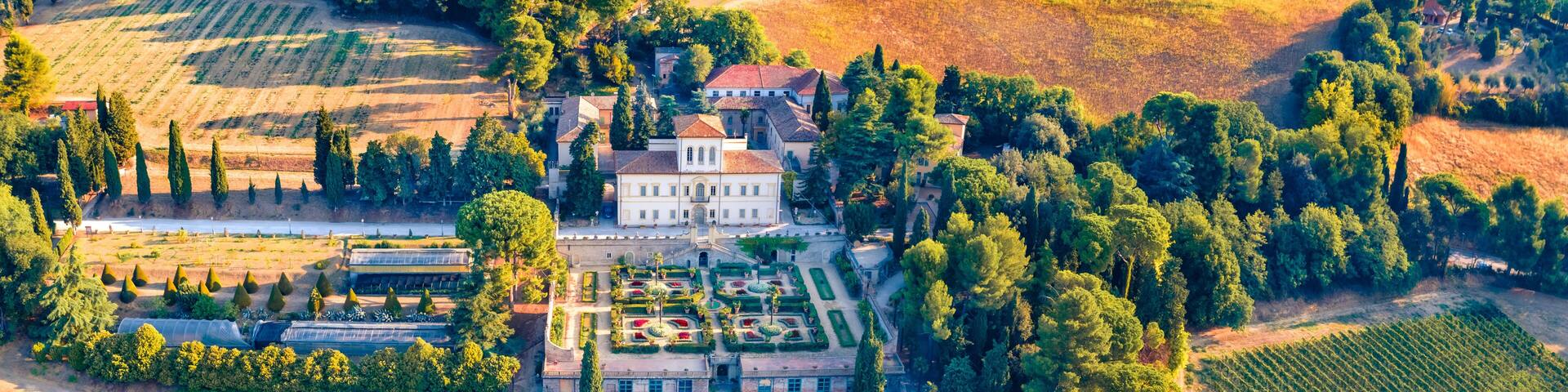 An aerial view of a large estate with expansive vineyards, a formal garden, and a prominent manor house.