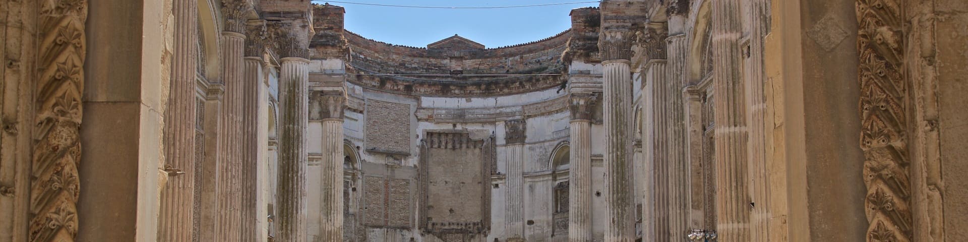 An ancient Roman amphitheater with columns and a central stage.