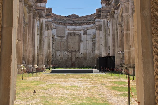 Ein römisches Amphitheater aus antiker Zeit mit Säulen und einer zentralen Bühne.