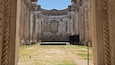 An ancient Roman amphitheater with columns and a central stage.