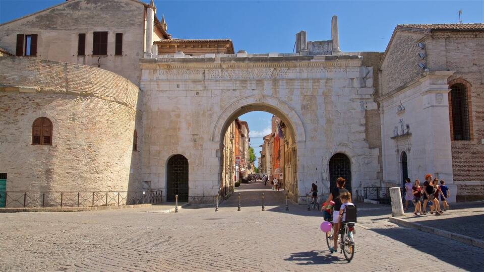 Arco di Augusto che include bicicletta e oggetti d\'epoca cosi come famiglia