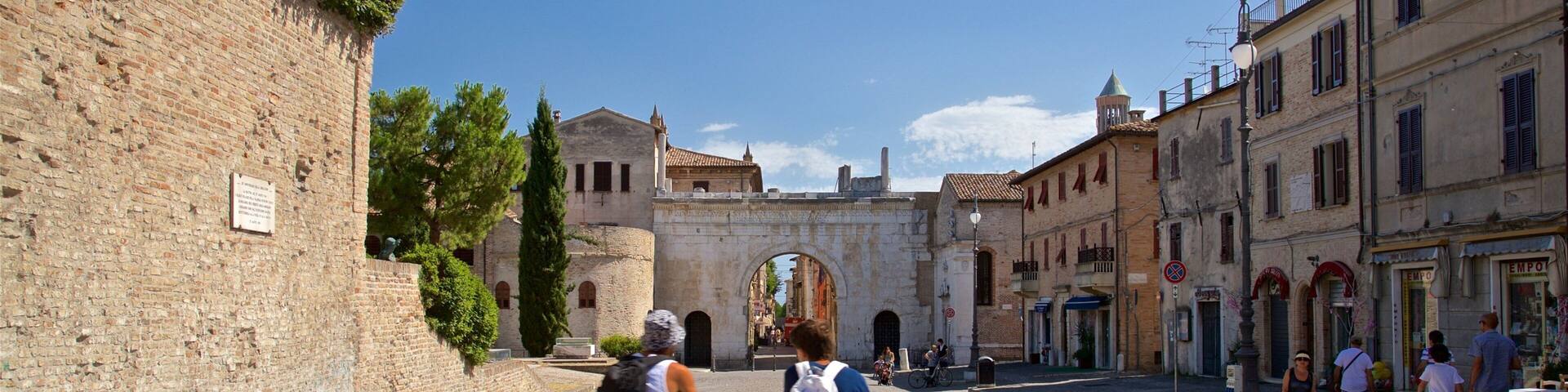 A historic street with cyclists, stone walls, and traditional buildings.