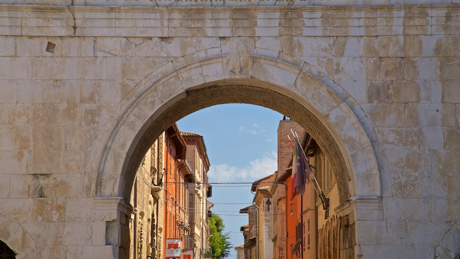 An arched stone gateway with inscriptions, leading to a street lined with historic buildings.