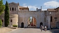 An ancient stone archway with people riding bicycles through it.