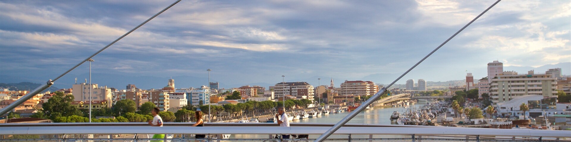 Un puente con vistas a un puerto deportivo y al paisaje urbano.