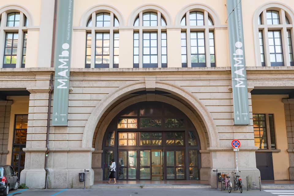 Ein Gebäude mit großen Bogenfenstern und einem Schild mit der Aufschrift 'MAMBO'.