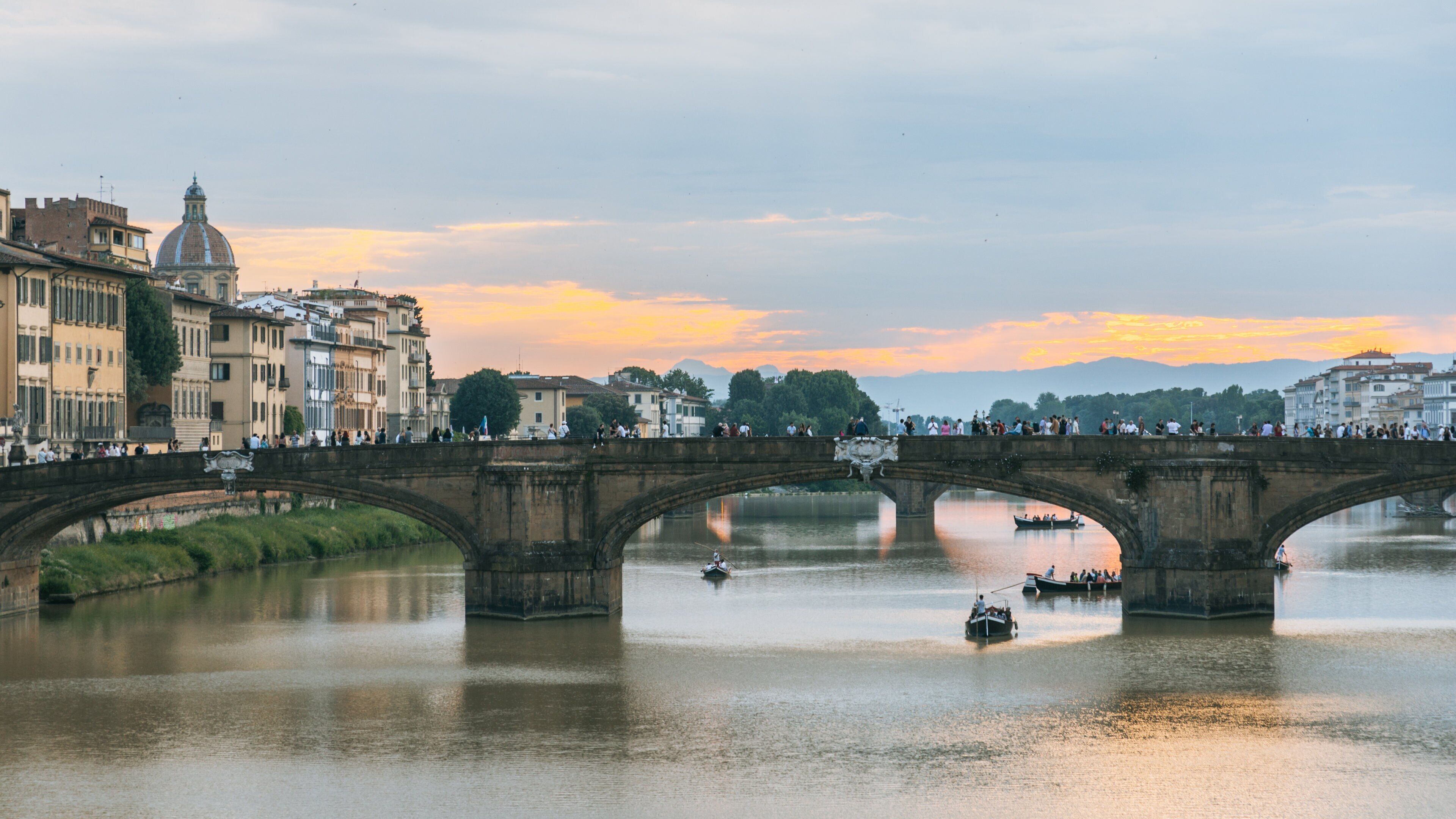 Arno River showing a bridge, a sunset and boating