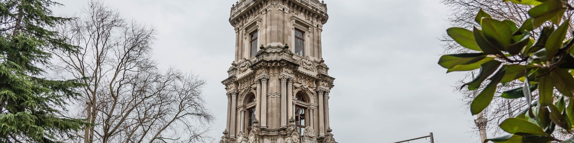 Una torre de reloj histórica con elaborados adornos y una cúpula al fondo.